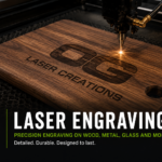 Laser engraving machine engraving the OG Laser Creations log onto a wooden cutting board with precision detail.